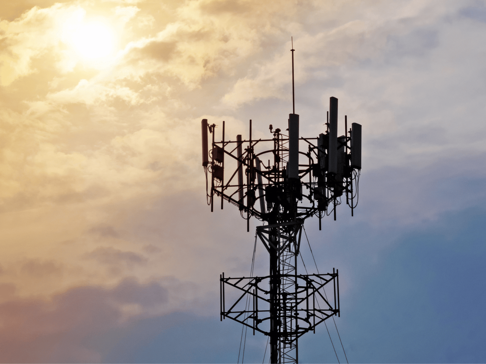 Business telecoms mast and antenna tower silhouetted against a cloudy sky