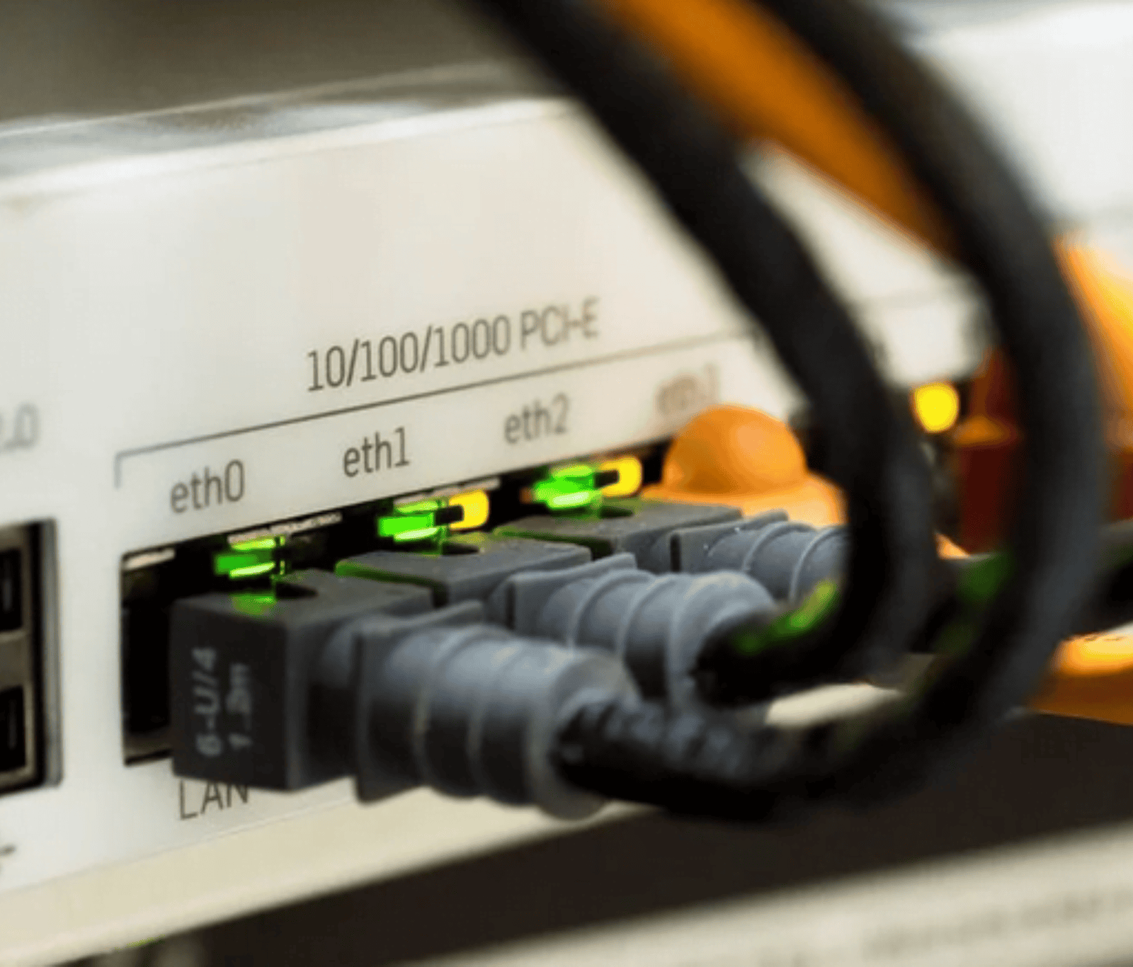 Close-up of Ethernet cables connected to a network switch with active status lights, representing wired connectivity and network infrastructure.