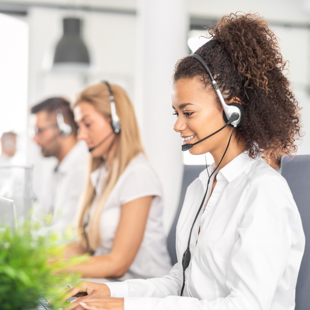 Smiley people smiling at a desk with a head set