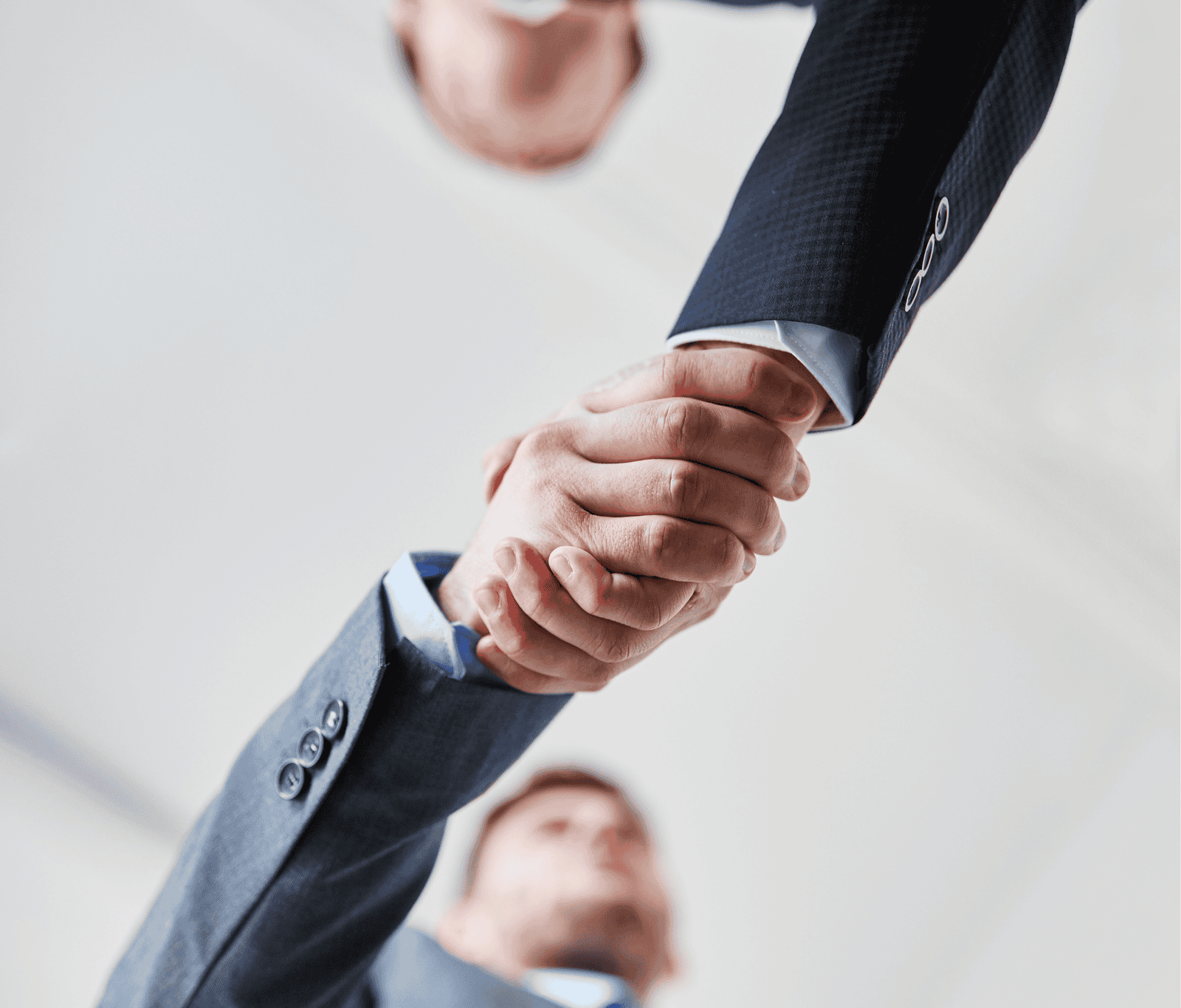 Low-angle view of two business professionals in suits shaking hands, symbolising agreement, trust, and professional partnership.